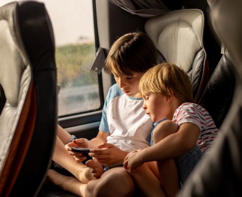 two children seated side by side on a charter bus rental